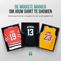 Drie ingelijste sportshirts: rood met nummer 19, zwart met nummer 13, en geel met nummer 23.