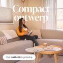 Vrouw met oranje vest leest boek zittend op beige bank, met draadloze Evite borstkolf. Past makkelijk in je kleding.