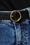 Zwarte riem met goudkleurige gesp, gedragen met een spijkerbroek.