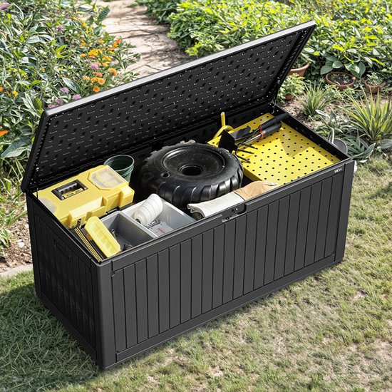 Open zwarte kunststof tuinopbergbox met ribbelpatroon, gevuld met tuingereedschap en een autoband.
