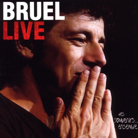 BRUEL LIVE: Close-up van Patrick Bruel met zijn handen voor zijn mond, kijkend naar rechts.