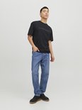 Man in een zwarte Jack & Jones t-shirt en blauwe jeans.