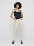 Model met een donkerblauwe top en crèmekleurige skinny jeans met rafelige zoom.