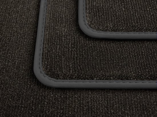 Gros plan détaillé de tapis de sol sombres et texturés avec des passepoils gris.