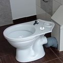 Witte toiletpot met een zilveren scharnieronderdeel geplaatst op de rand.