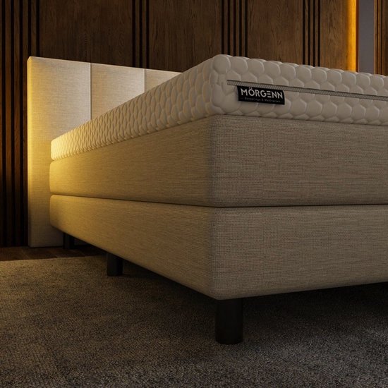 Luxe beige boxspring met matras en een label met 'Mörgenn'. Zwart metalen pootjes.