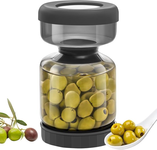 Bocal en verre rempli d'olives vertes, avec branche d'olivier et cuillère d'olives à côté.
