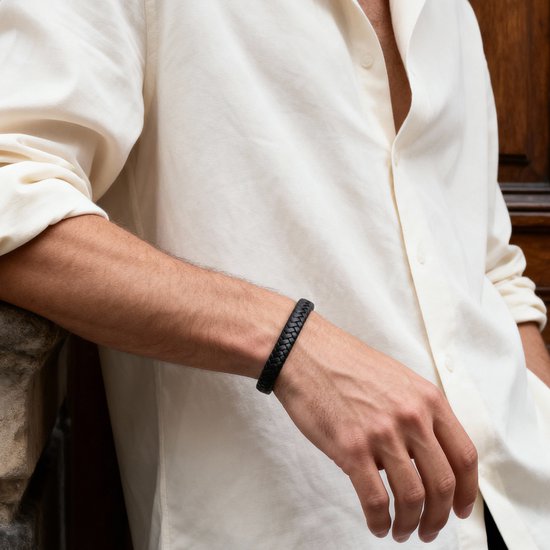 Zwarte gevlochten leren armband gedragen om de pols van een man met een wit hemd.