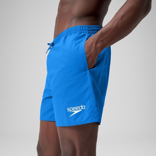 Short de bain bleu Speedo avec logo blanc, porté par un homme la main dans la poche.