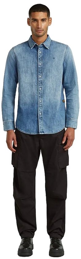 Man draagt een blauw denim overhemd met lange mouwen en zwarte cargo broek.