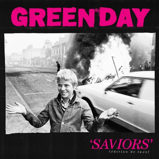Albumcover met de titel 'Green Day Saviors (édition de luxe)'. Een jongen met wapperende armen voor een brandende auto.
