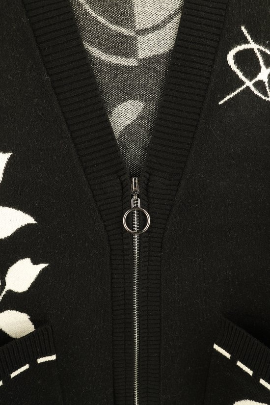 Detail van de zilverkleurige ritssluiting met ringtrekker op een zwart gebreid vest.
