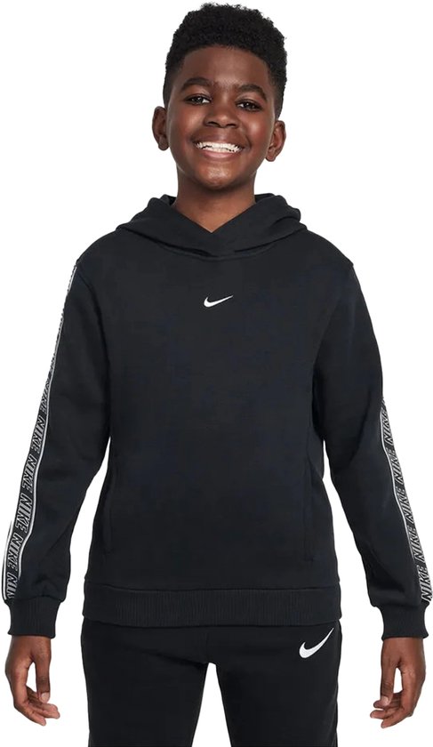 Garçon souriant portant un sweat à capuche Nike noir. Bande Nike sur les manches. Logo Nike sur la poitrine et le pantalon.