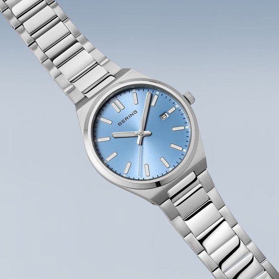 Zilverkleurig herenhorloge met blauwe wijzerplaat. De wijzerplaat heeft een datumweergave. Het horloge heeft een metalen band.