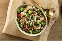 Ovale schaal gevuld met quinoa salade met broccoli, olijven en rode paprika.