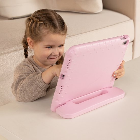 Meisje met vlechten gebruikt een roze tablet hoes als standaard.