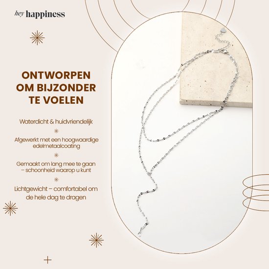 Gelaagde zilverkleurige ketting met fijne schakels en een Y-vormige drop, op een lichte achtergrond.