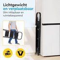 Man draagt een ingeklapte zwarte metalen huishoudtrap met 3 treden in een keuken.