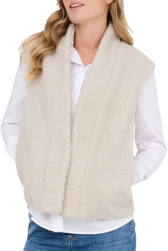 Close-up van een vrouw in een gebroken witte teddy gilet over een wit overhemd, met handen in de zakken.