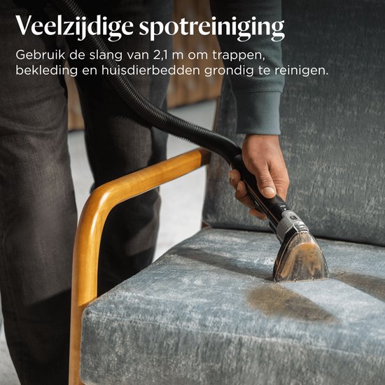 Een hand gebruikt het opzetstuk van de BISSELL HydroSteam tapijtreiniger om een blauwe stoel schoon te maken.
