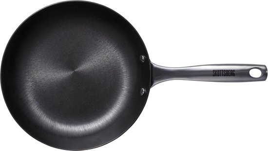 Zwarte Skottsberg koekenpan met metalen handvat, op zwarte achtergrond.
