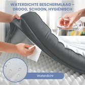Water wordt gegoten op een hondenkussen dat wordt schoongemaakt, wat de waterdichte eigenschappen aantoont.