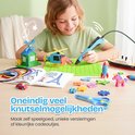 Meisje met blauwe 3D-pen maakt een raket op een groene mat. Veel knutselwerkjes zoals een molen, helikopter en eenhoorn.