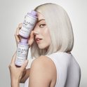Model met kort, wit haar houdt twee Olaplex flessen omhoog: No.4P en No.5.