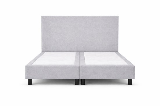 Grijze boxspring met hoofdbord, staand op zwarte pootjes.