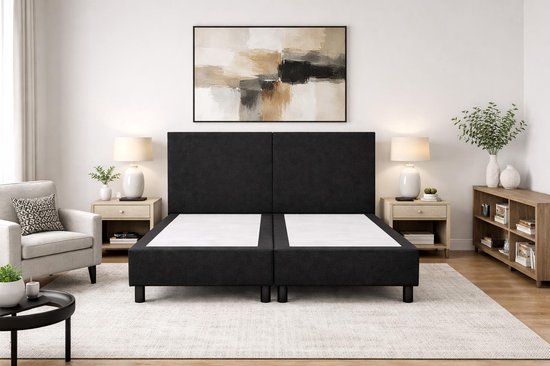 Zwart boxspringbed met hoog hoofdbord, twee boxen, zwarte poten en witte matrassen.