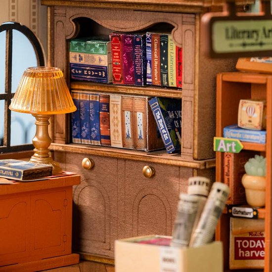 Gedetailleerd interieur van een miniatuur boekenwinkel met boekenplanken, een lamp en een kast.
