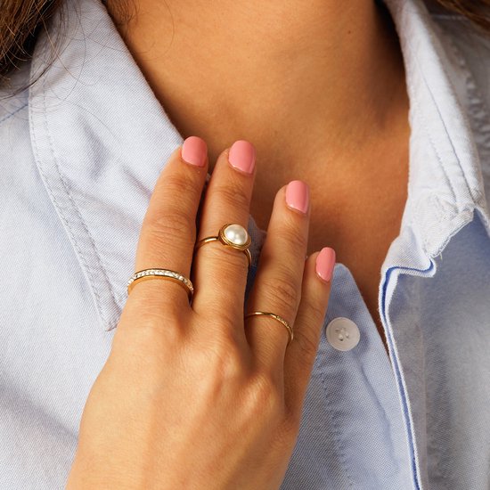 Vrouwelijk hand met gouden ringen, waarvan één met parel.