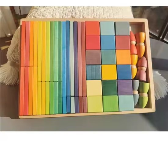 Houten speelgoedblokken en kabouterfiguurtjes in een houten bak, gerangschikt op kleur en vorm, met regenboogkleuren.