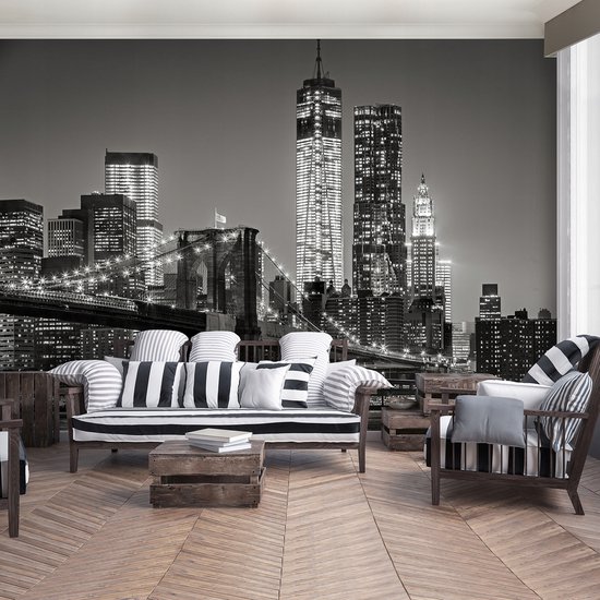 Fotobehang van New York skyline met Brooklyn Bridge 's nachts, zwart-wit. Zithoek met gestreepte banken.