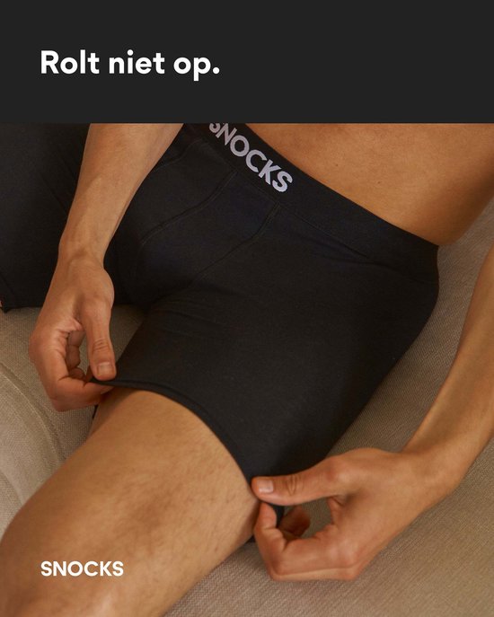 Gedetailleerde weergave van man in zwarte boxershorts, die de stof aan het been omhoog trekt.