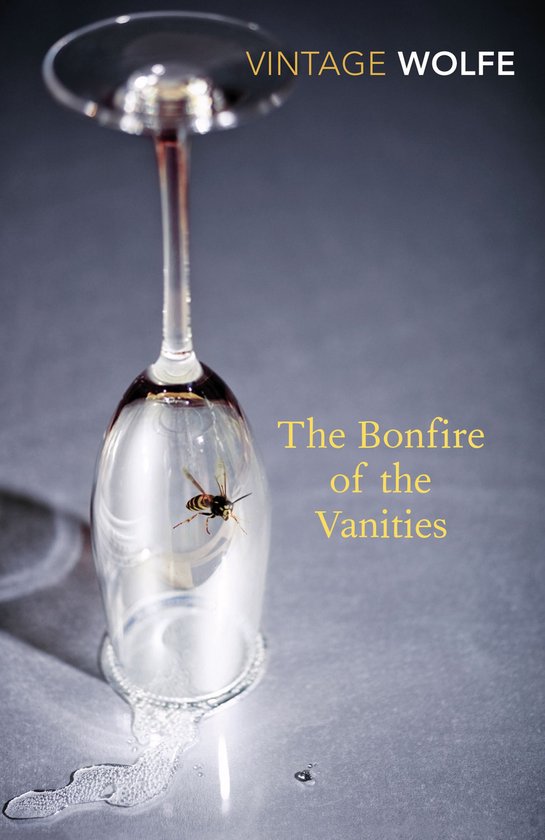 Livre 'The Bonfire of the Vanities' avec un guêpe sur le calice en verre et du liquide renversé.