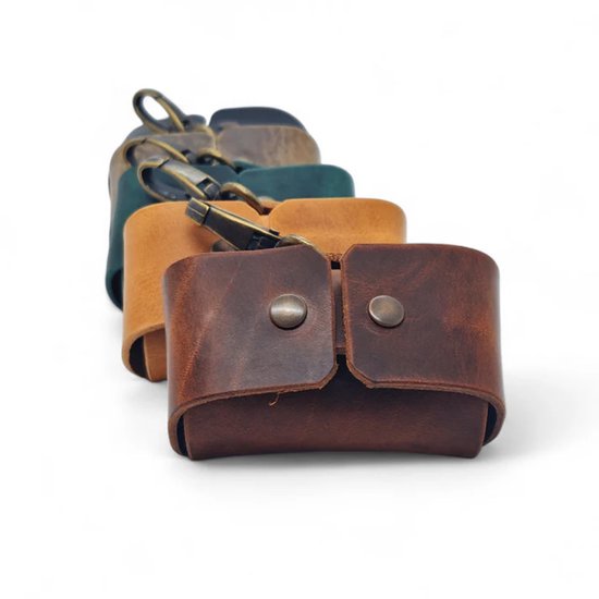 Vier poepzakjeshouders in bruin, camel, groen en donkerblauw, met metalen clip.
