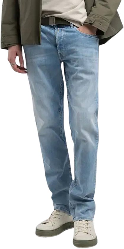 Homme en jean bleu clair, t-shirt blanc et veste verte.