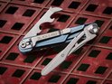 Blauwe multitool met mes, flesopener en schroevendraaier opengeklapt op rood rasteroppervlak.
