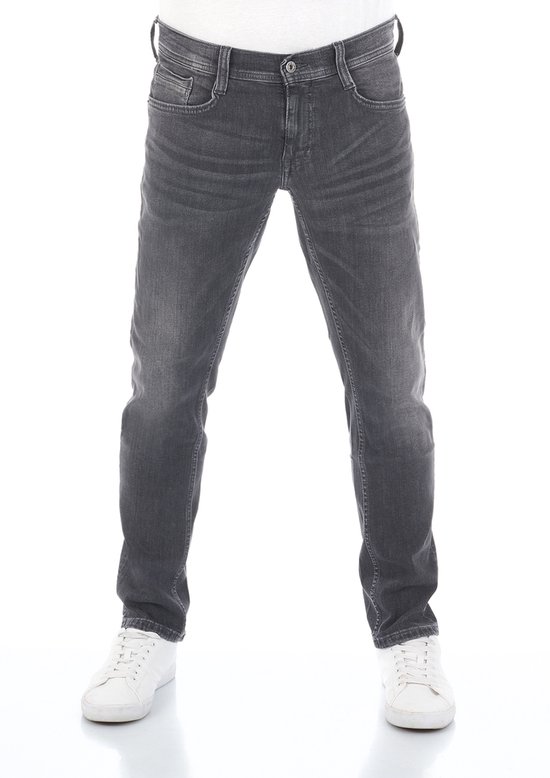 Vooraanzicht van een model in zwarte Mustang tapered fit jeans met lichte wassing, gecombineerd met witte sneakers.