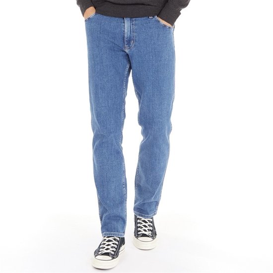 Jean Wrangler bleu avec patch logo marron au dos, porté par un homme.
