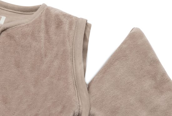 Gedetailleerde foto van de schouder en rits van een mouwloze beige slaapzak.