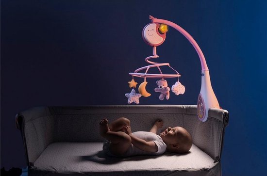 Baby ligt in een wieg met een roze muziekmobiel met maan, sterren en teddybeer.