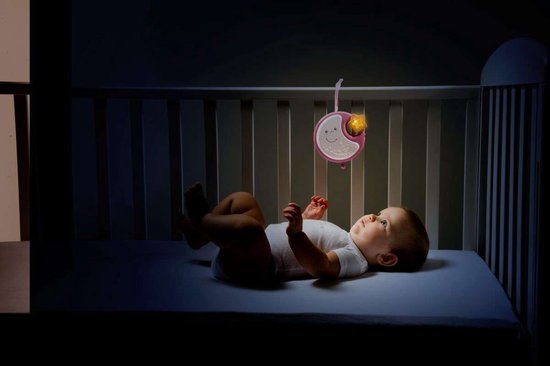 Baby ligt in een ledikant onder een roze muziekmobiel met een maan en sterren.