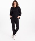 Model in zwarte outfit met zwart T-shirt, zwarte broek met strikceintuur en zwart vest met knopen.