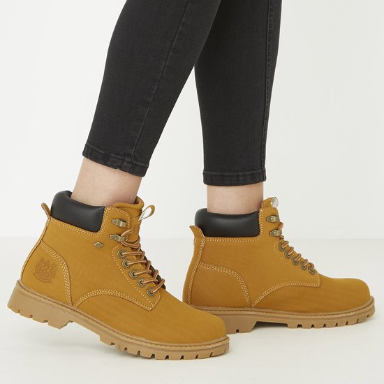 Vrouw met zwarte jeans draagt gouden bruine veterlaarsjes met dikke zolen.