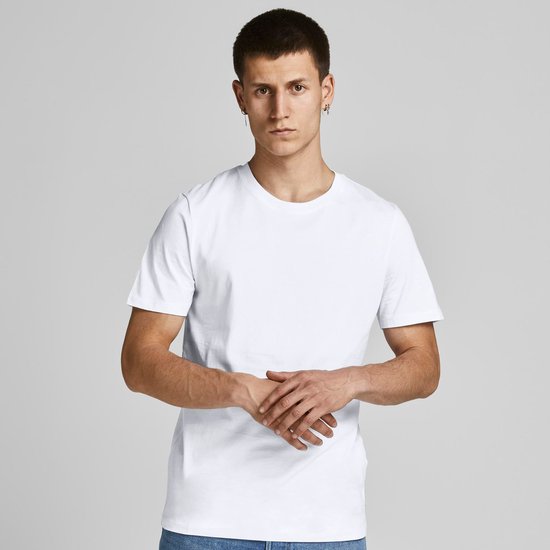 Man draagt een wit T-shirt met gevouwen handen.