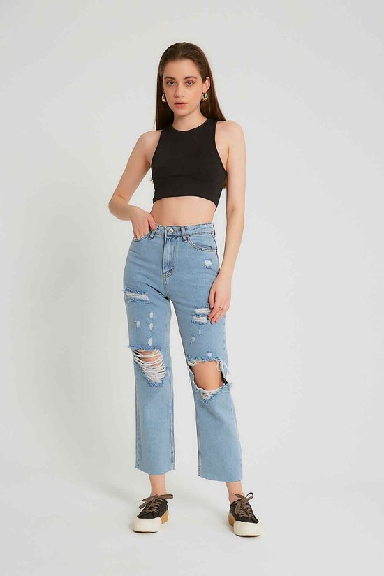 Model in een spijkerbroek met hoge taille, lichtblauw en gescheurd, met wijde pijpen en rafelige zoom.