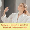 Een vrouw in een witte badjas spuit zichzelf in met Zwitsal Eau de Toilette.