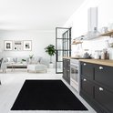 Tapis shaggy noir à poils longs dans une cuisine moderne avec des armoires et un comptoir noirs.